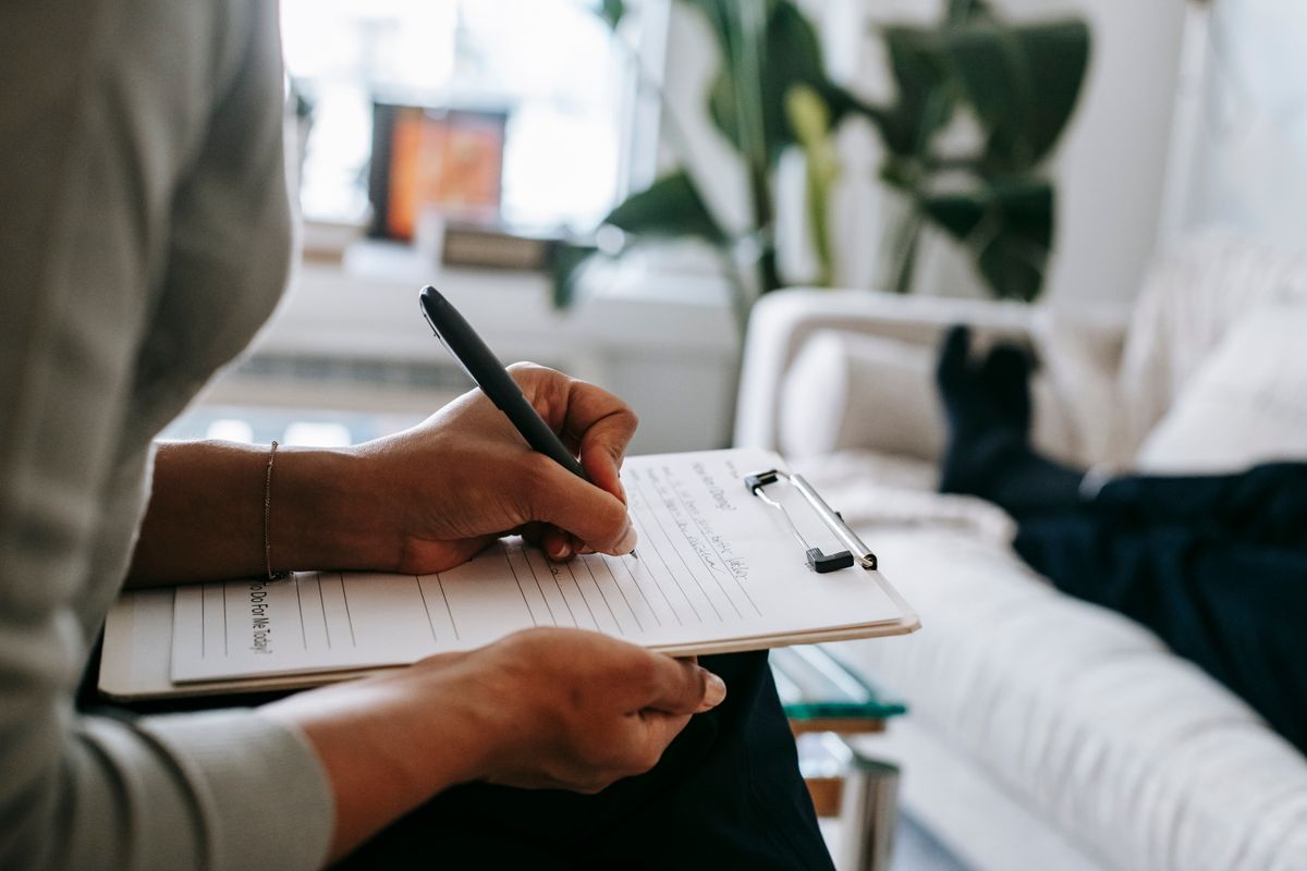 A clinician taking notes during a consultation