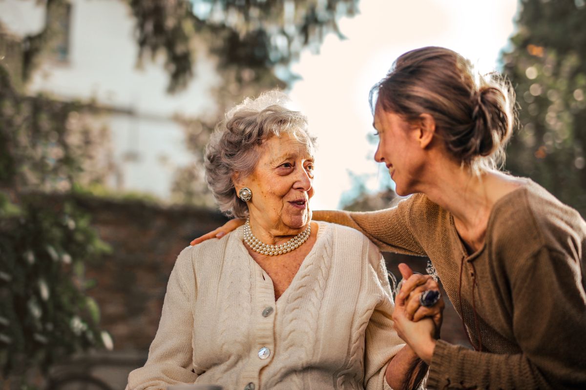 A carer speaking with an older adult outdoors